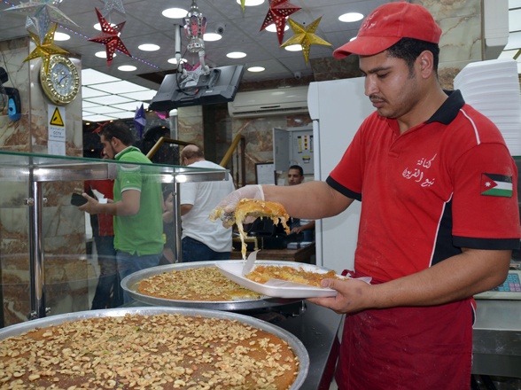 A worker serves kunafa at a restaurant in Amman on Saturday (Photo by Osama Aqarbeh)